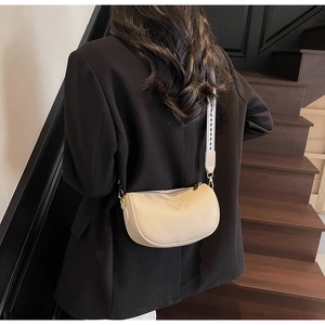 Close-up of beige lychee leather crossbody bag with geometric woven shoulder strap