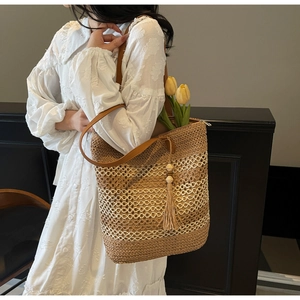 Détail du sac cabas en paille tissé main avec anses en cuir marron et pompon décoratif