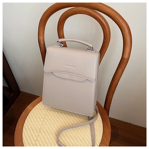 Detail of minimalist leather handbag with Fashion & Bag embossing on textured chair