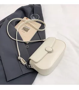 Close-up of cream shoulder bag with litchi texture leather and round metal lock buckle