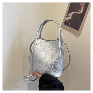 Macro detail of silver bucket bag showing textured lychee leather and dual handles