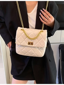 Fashionable white quilted crossbody bag with gold chain strap worn by a model