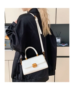Nahaufnahme einer weißen Lederhandtasche mit goldenem Verschluss und Trageriemen