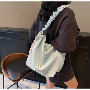 Detail of light blue matte leather tote bag with pleated shoulder strap and brand label