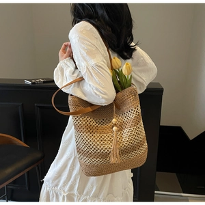 Détail du sac cabas en paille tissée avec pompons et perles en bois style vacances