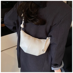 Detail view of a cream croissant bag with pleated leather and knotted shoulder strap