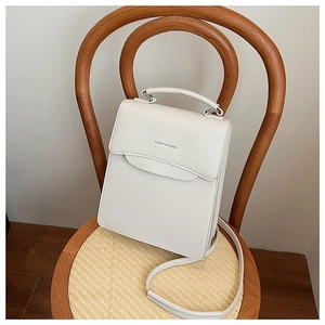 Detailed shot of white PU leather handbag with Fashion & Bag text on a vintage chair