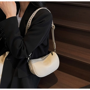 Close-up of beige lychee leather bag with woven shoulder strap and metal zipper detail