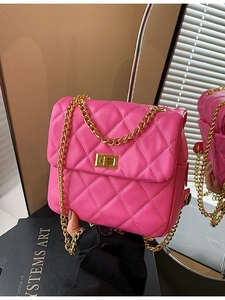 Magenta quilted crossbody bag with gold chain strap and turn-lock closure in home setting