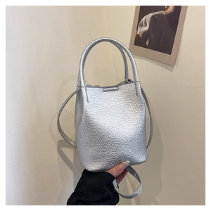 Detail of silver bucket bag featuring textured lychee pattern leather and top handle