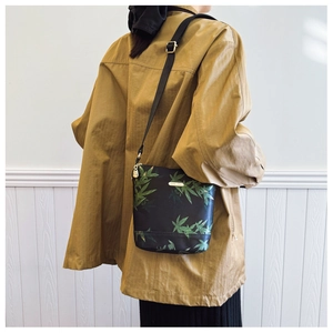 Detail of waterproof nylon bag with leaf pattern, gold hardware and adjustable strap