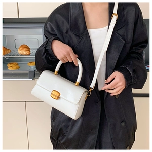 Detail einer minimalistischen weißen Leder-Handtasche mit goldenem Metallschloss-Verschluss