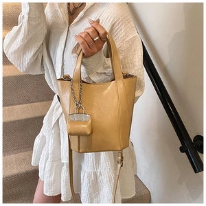 Detail of ginger yellow bucket bag with retro pleated texture and mini decorative pouch