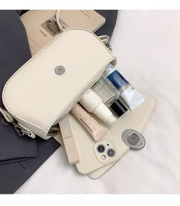 Spacious interior of minimalist cream shoulder bag showing phone and cosmetics storage