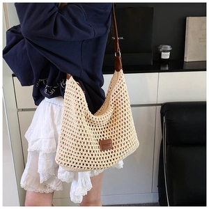Detail of hand-woven mesh texture and brown leather strap on beige tote bag