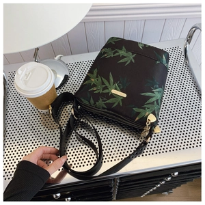 Macro detail of waterproof nylon crossbody bag with green leaf pattern and gold zippers