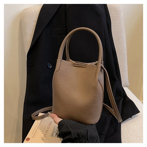 Close-up of brown lychee grain leather bucket bag with top handle and shoulder strap