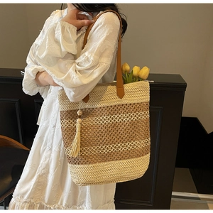 Sac fourre-tout en paille avec bandoulières en cuir marron et pompon beige sur mannequin