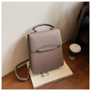Detail of taupe leather handbag with FASHION & BAG lettering on elegant book display