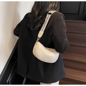 Detail of cream lychee leather half-moon bag with patterned wide woven shoulder strap
