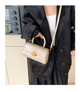 Modell mit schicker beige quadratischer Handtasche mit goldener Schnalle im Innenraum