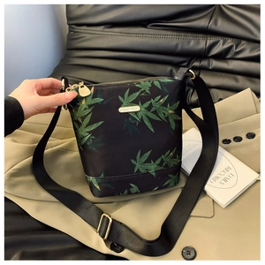 Detail of waterproof nylon bucket bag with green maple leaf pattern and metal logo