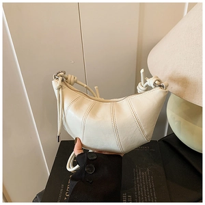 Detailed view of the white quilted crescent bag featuring stylish knotted strap and zip closure