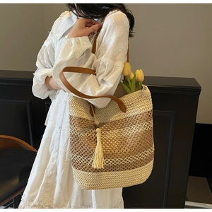 Détail d'un sac cabas en paille tressée avec des rayures et un gland en cuir élégant