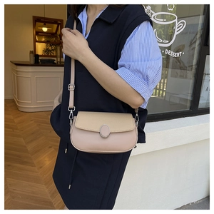 Detail of minimalist pink and beige patchwork saddle bag with oval metal buckle