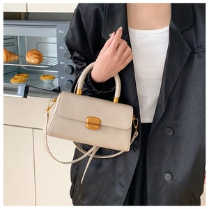 Detail der cremeweißen Leder-Mini-Handtasche mit goldener Schnalle und festem Griff
