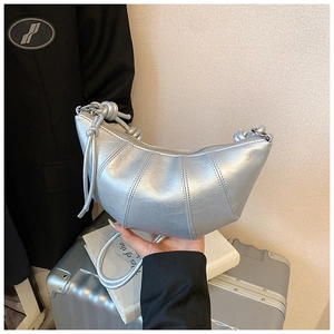 Close-up of silver croissant bag featuring a metallic finish and knot handle detail