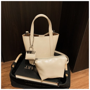 Creamy bucket bag set with matching pouch and mini charm on a rustic background