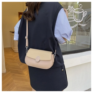 Detail of a contrast leather crossbody bag with silver oval metal lock and adjustable strap