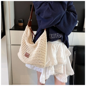 Detail of hollow woven tote bag featuring brown leather handles and zipper closure