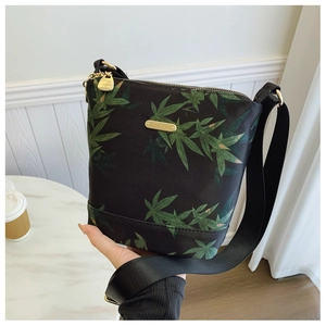 Detail of waterproof nylon bag showing green leaf print and golden metal logo plate