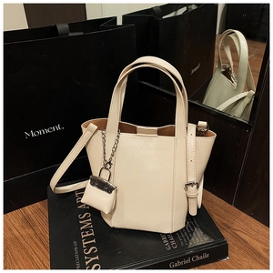 Close-up of cream white tote bag with mini pouch charm and adjustable shoulder strap