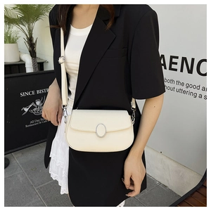 Detail of a creamy beige faux leather shoulder bag with a silver oval buckle and pebble texture