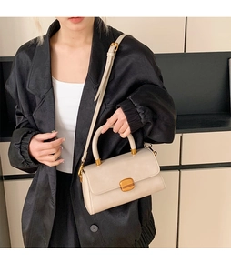 Detailansicht der beigefarbenen Umhängetasche aus Leder mit goldener Schnalle am Model
