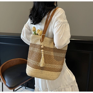 Détail d'un sac cabas en paille tissé à la main avec anses en cuir et pompon décoratif