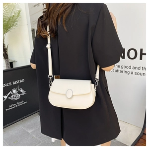 Close-up of creamy white lychee leather saddle bag with silver oval metal buckle details