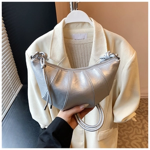 Detail of silver metallic crescent bag featuring vertical quilting and woven handle