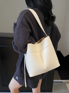 Chic white lychee leather bucket bag with shoulder strap shown on a model