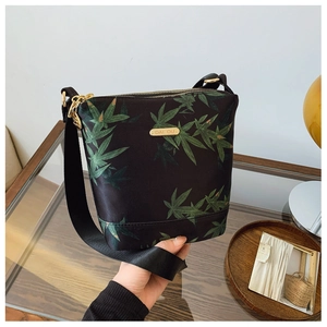 Close-up of lightweight waterproof nylon crossbody bag with green maple leaf pattern