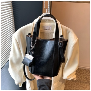 Detail of black pebbled leather bucket bag with silver chain and mini pouch charm
