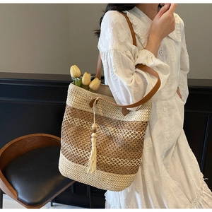 Détail du sac cabas rayé en paille avec bandoulières en cuir et pompon à perles