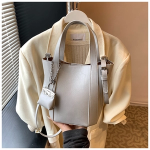 Detail of grey leather bucket bag featuring a unique mini bag charm on the handle
