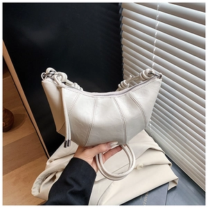 Detail of cream pleated leather crescent bag with unique knot handle design and zipper