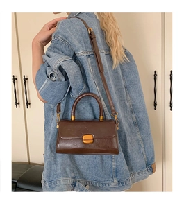 Braune Vintage-Ledertasche mit goldenem Verschluss, getragen von einem Modell im Alltag