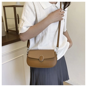 Close-up of brown saddle bag featuring textured leather panels and silver metal buckle