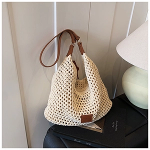 Detail of hollow woven tote bag with brown leather handles and rectangular patch